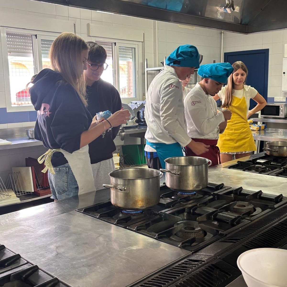 Alumnado preparando los platos en la cocina, con las ollas al fuego